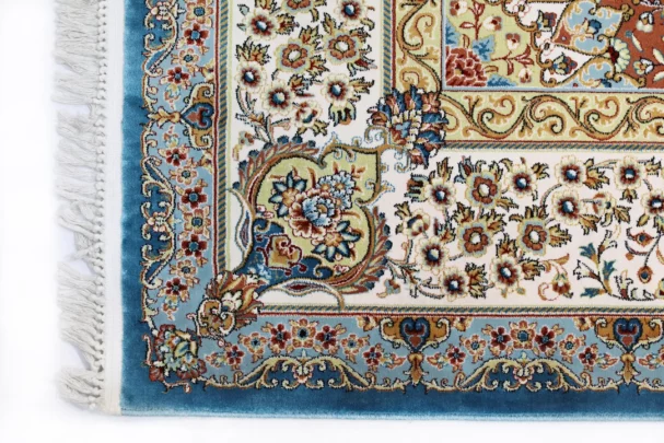 A close-up of a Qaleen Carpets rug with intricate floral patterns and a blue border, showcasing the company's high-quality