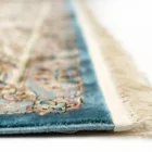 A close-up of a Qaleen Carpets rug with intricate patterns and a blue border, showcasing the quality and craftsmanship of