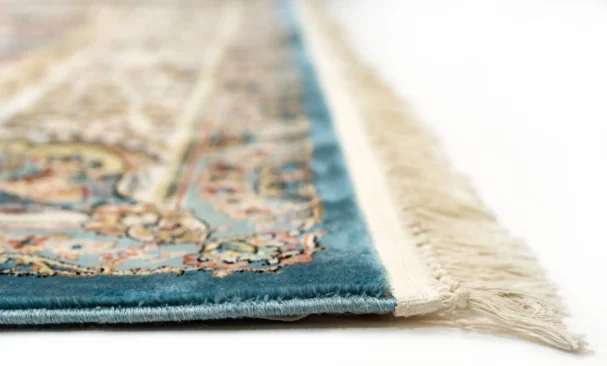 A close-up of a Qaleen Carpets rug with intricate patterns and a blue border, showcasing the quality and craftsmanship of