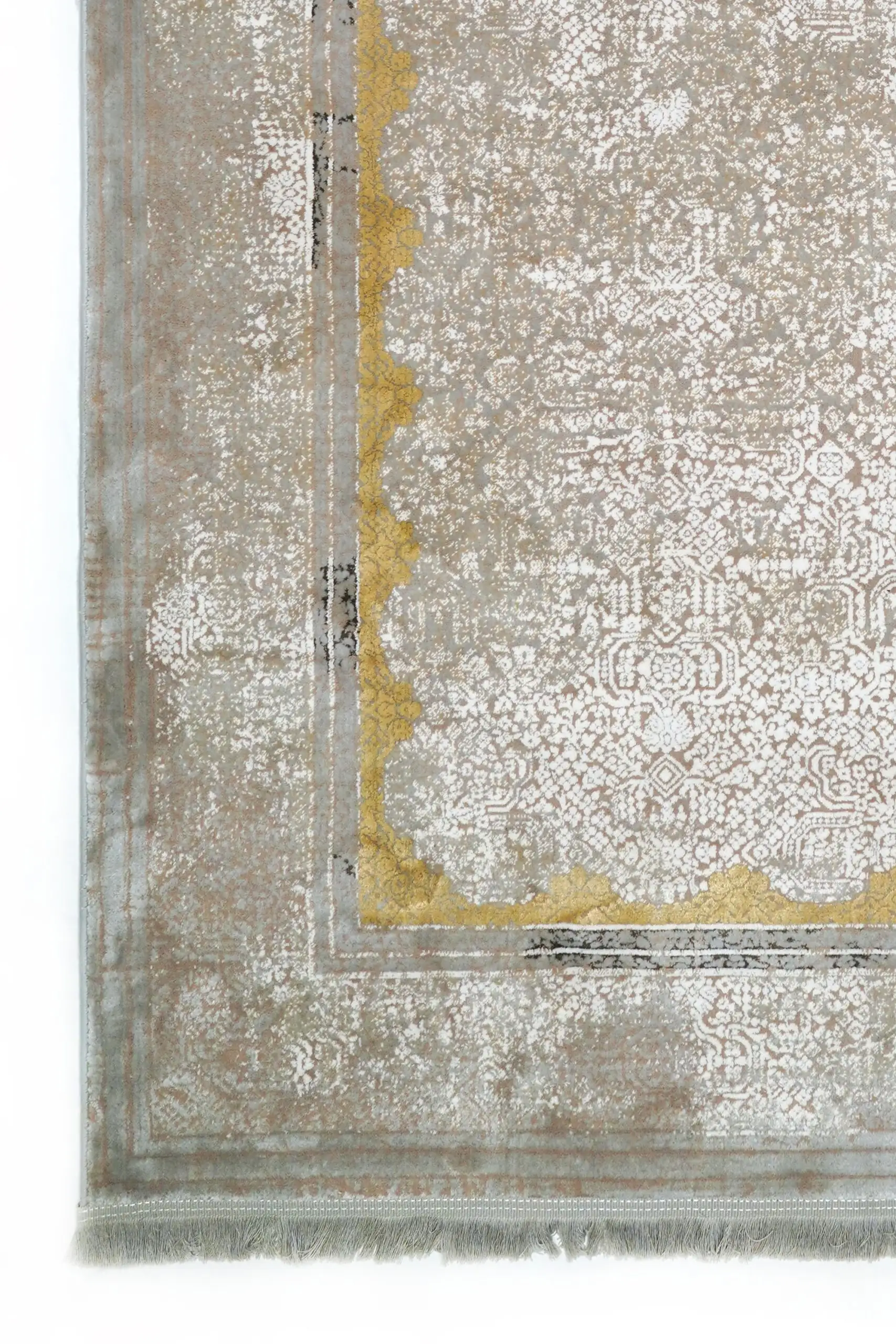 A close-up of a Qaleen Carpets rug with a gold border and intricate patterns, set against a white background