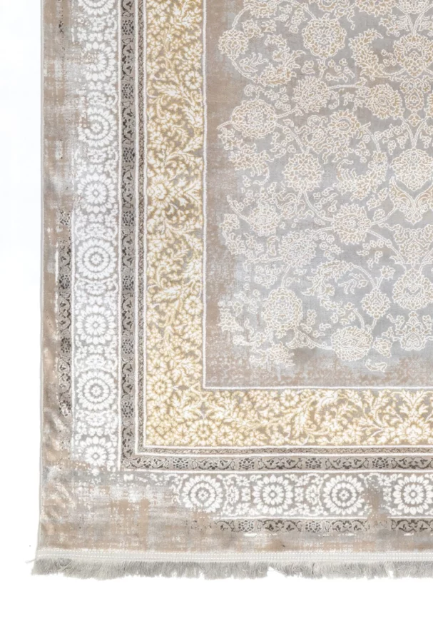 A close-up of a Qaleen Carpets rug with a floral pattern in a neutral color palette, featuring a central design and a border