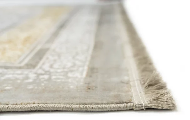 A close-up of a Qaleen Carpets rug's edge, with a focus on the fringe and the rug's design