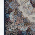 A qaleen carpet with a floral pattern and a fringe at the bottom, showcasing a mix of blue, red, and white colors