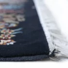 A close-up of a Qaleen Carpets rug's edge, with a focus on the intricate design and the soft, white fringe