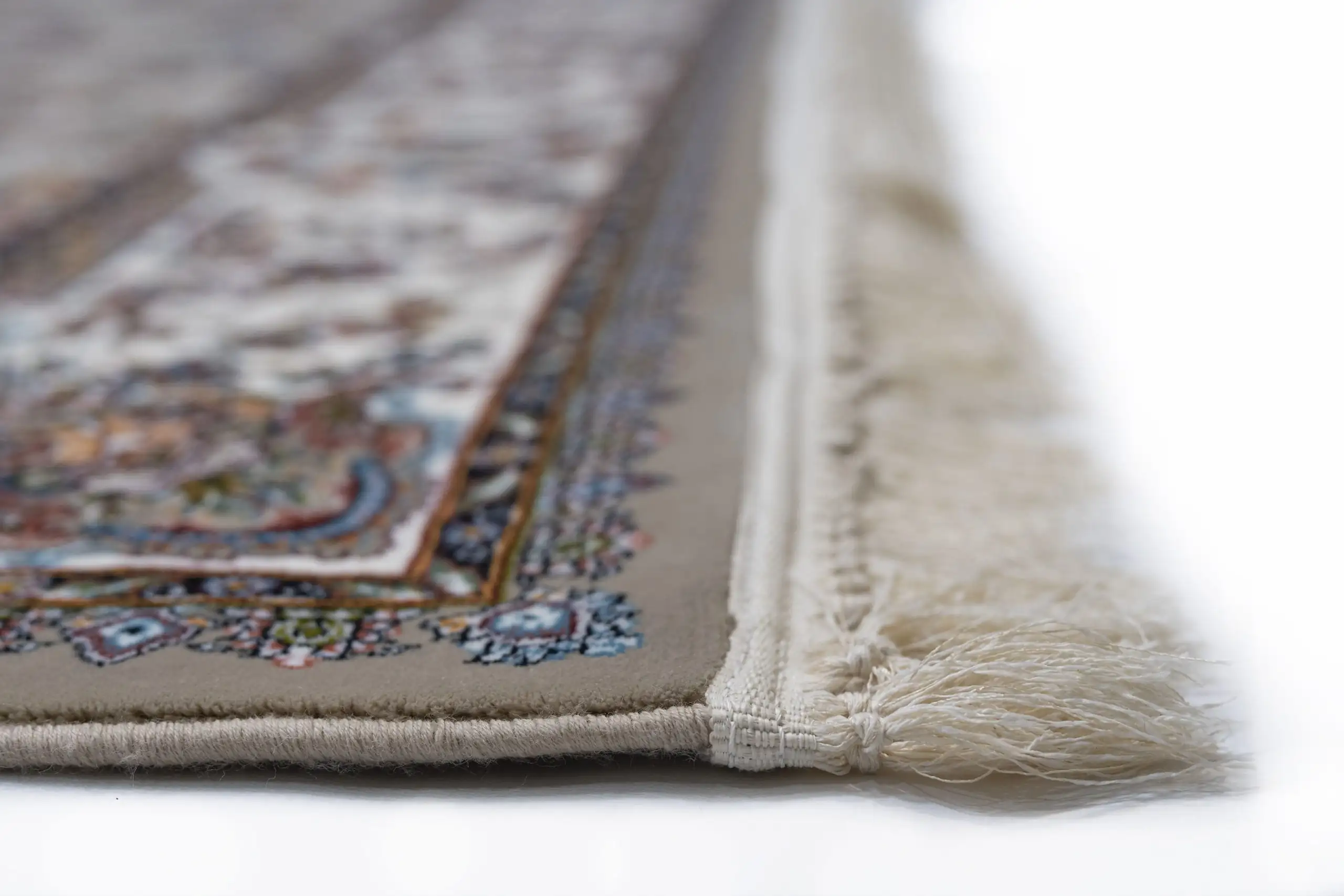 A close-up of a Qaleen Carpets rug with intricate patterns and a fringe on the edge, showcasing its high-quality