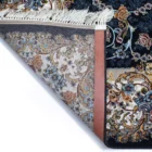 A close-up of a Qaleen Carpets rug with a floral pattern, featuring a mix of blue, gold, and white colors, with a fringe on
