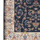 A close-up of a Qaleen Carpets rug with a dark blue background and intricate floral patterns, featuring a mix of roses,