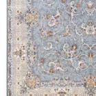 A close-up of a Qaleen Carpets rug with a grey and cream patterned design, featuring intricate floral and vine motifs, set