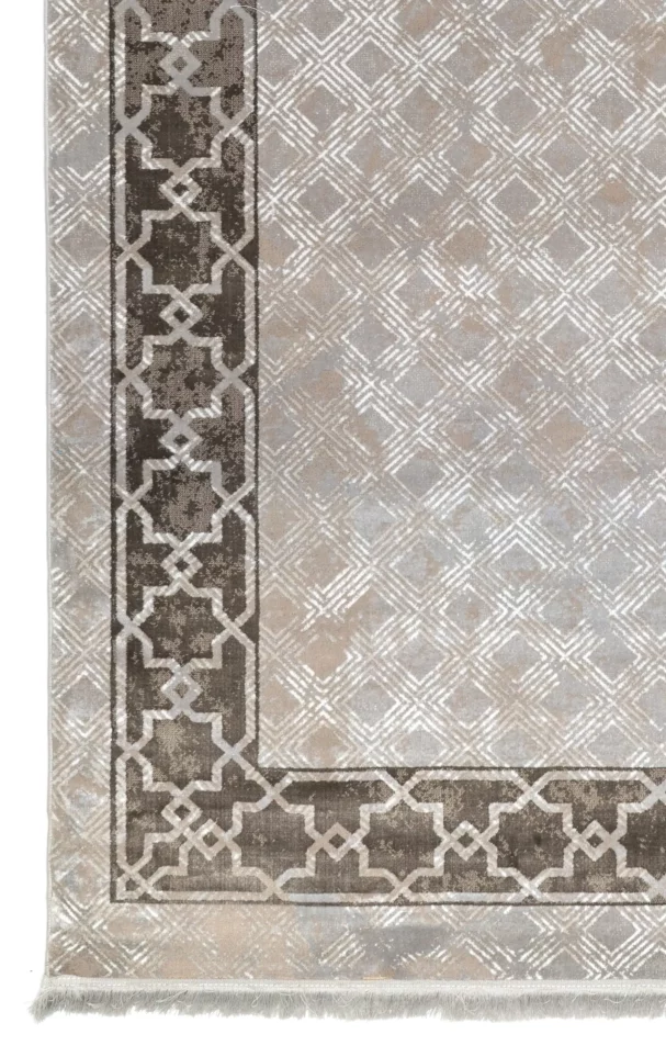 A close-up of a Qaleen Carpets rug with a geometric pattern and a border, showcasing the intricate design and quality of the