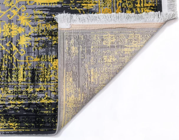 A close-up of a rug with a yellow, black, and grey pattern, with a white fringe at the edge, from the Qaleen Carpets