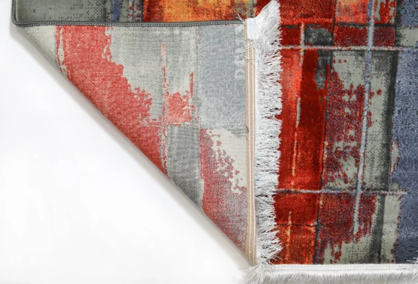 A close-up of a vibrant, hand-woven Qaleen Carpets rug with a unique, abstract design, featuring a mix of red, orange, and
