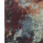 A close-up of a Qaleen Carpets rug with a mix of red, blue, and white colors, featuring a unique blend of patterns and