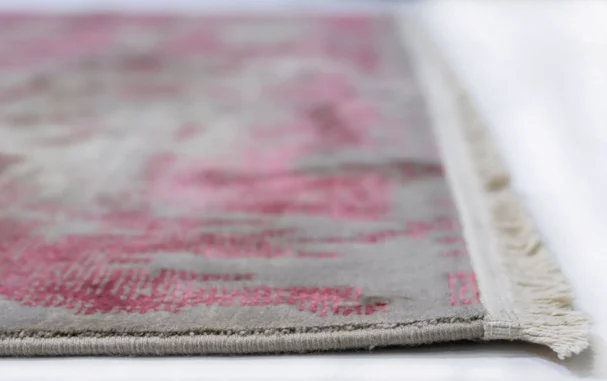 A close-up of a Qaleen Carpets rug, with a focus on the intricate patterns and textures of the carpet's edge, showcasing the