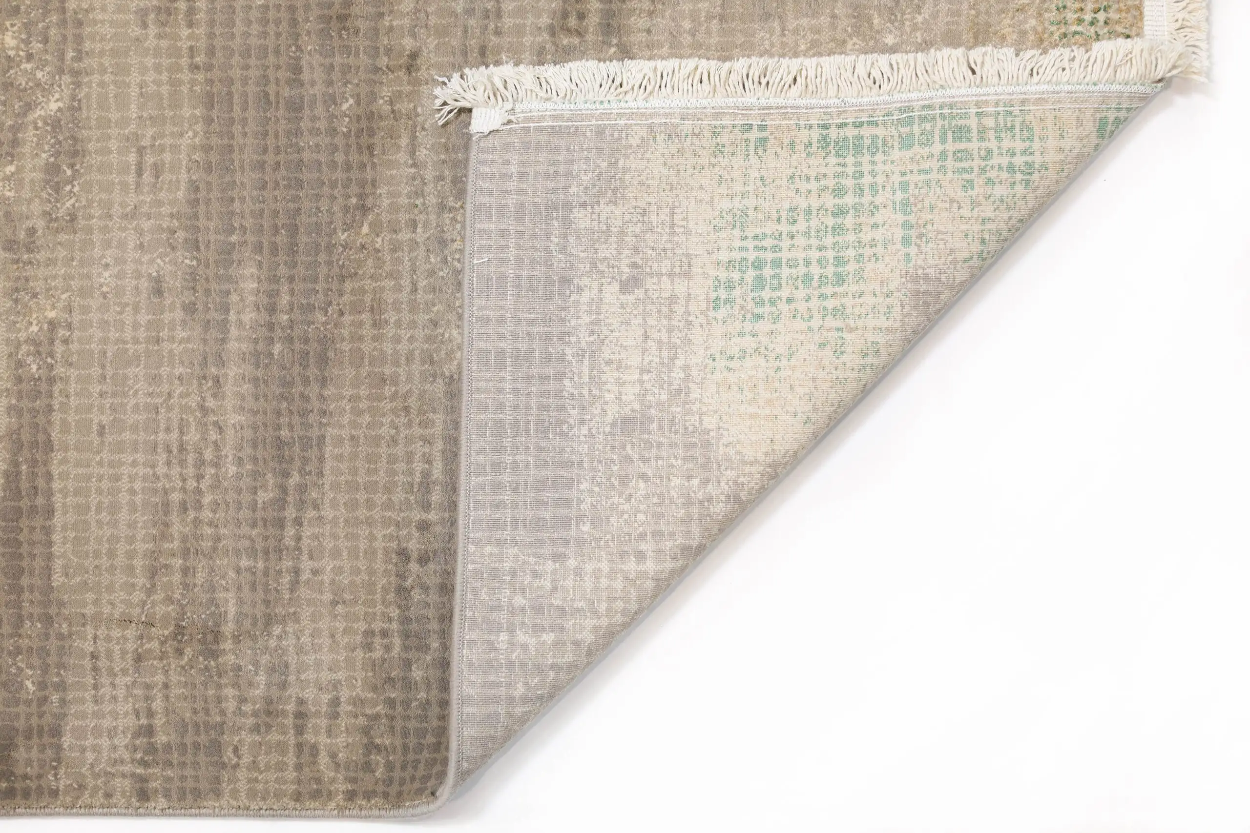 A close-up of a rug's corner, with a subtle pattern and a fringe of white, made by Qaleen Carpets