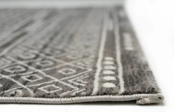A close-up of a gray and white area rug with a geometric pattern, made by Qaleen Carpets