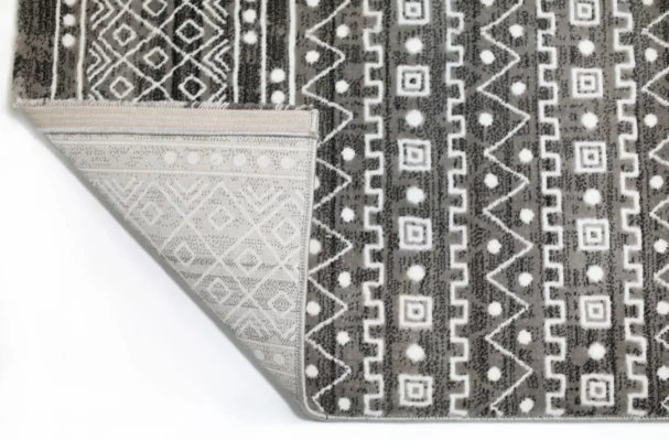 Qaleen Carpets A close-up of a rug with a patterned design, with the corner folded and the edge of the rug visible