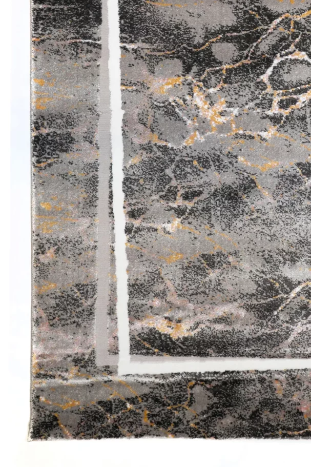 A close-up of a Qaleen Carpets rug with a dark, marbled pattern and gold and white accents, set against a white background