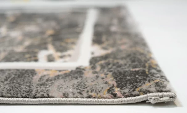 A close-up of a rug's edge, with a focus on the intricate design and the Qaleen Carpets brand