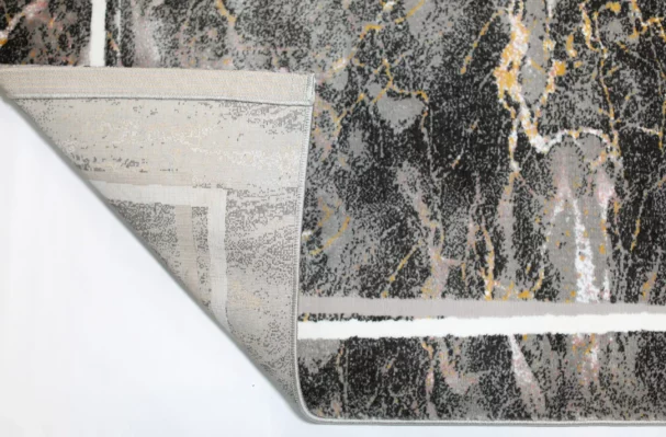 A close-up of a Qaleen Carpets rug with a unique, abstract design featuring a mix of dark and light colors, with a focus on