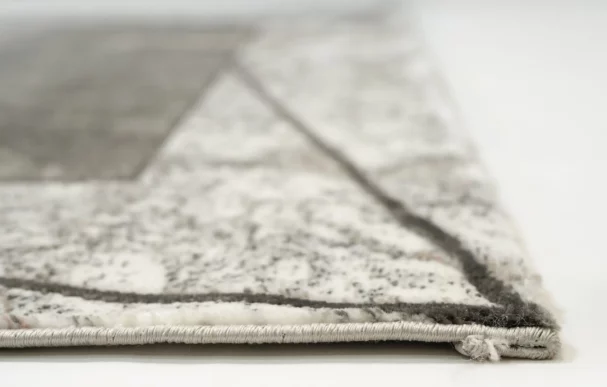 A close-up of a white and grey rug with a subtle, intricate pattern, made by Qaleen Carpets