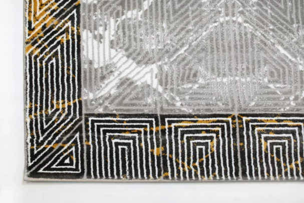 A close-up of a Qaleen Carpets rug with a geometric pattern, featuring a mix of black, white, and gold colors