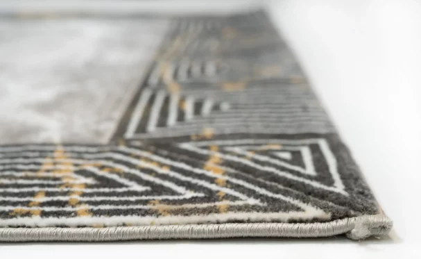 A close-up of a rug's edge, with a focus on the intricate pattern and the Qaleen Carpets brand