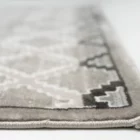 A close-up of the edge of a Qaleen Carpets rug, with a focus on the intricate design and the soft, plush texture of the