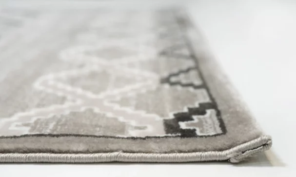 A close-up of the edge of a Qaleen Carpets rug, with a focus on the intricate design and the soft, plush texture of the