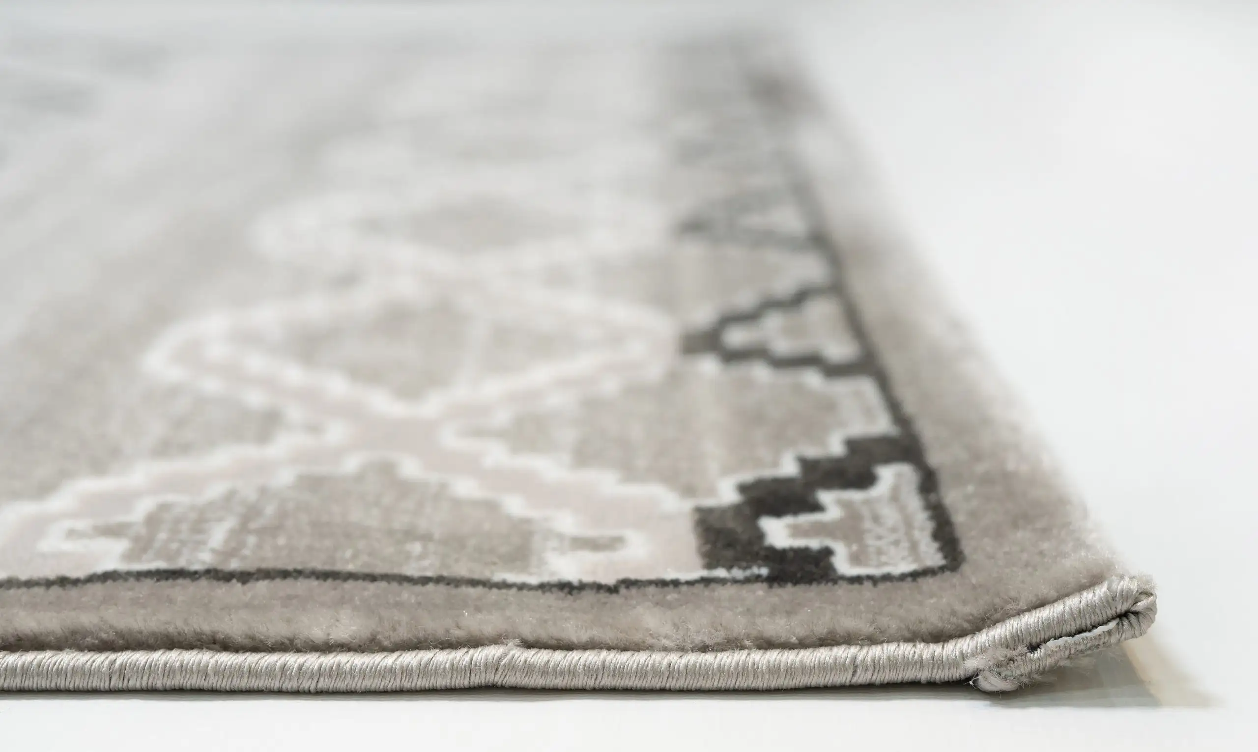 A close-up of the edge of a Qaleen Carpets rug, with a focus on the intricate design and the soft, plush texture of the