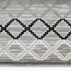 A close-up of a gray and white area rug with a geometric pattern, made by Qaleen Carpets