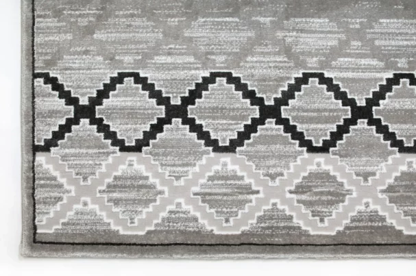A close-up of a gray and white area rug with a geometric pattern, made by Qaleen Carpets