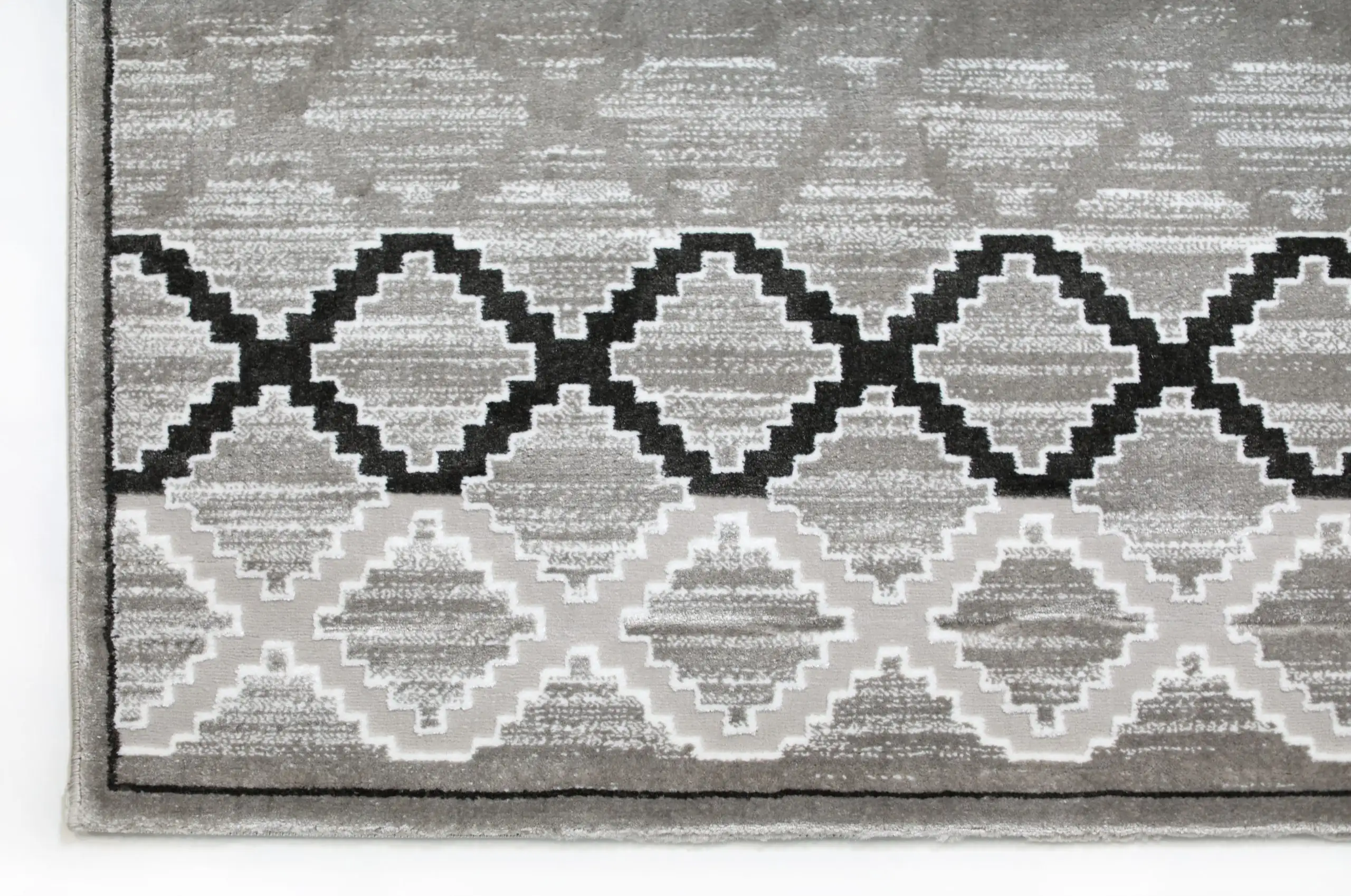 A close-up of a gray and white area rug with a geometric pattern, made by Qaleen Carpets