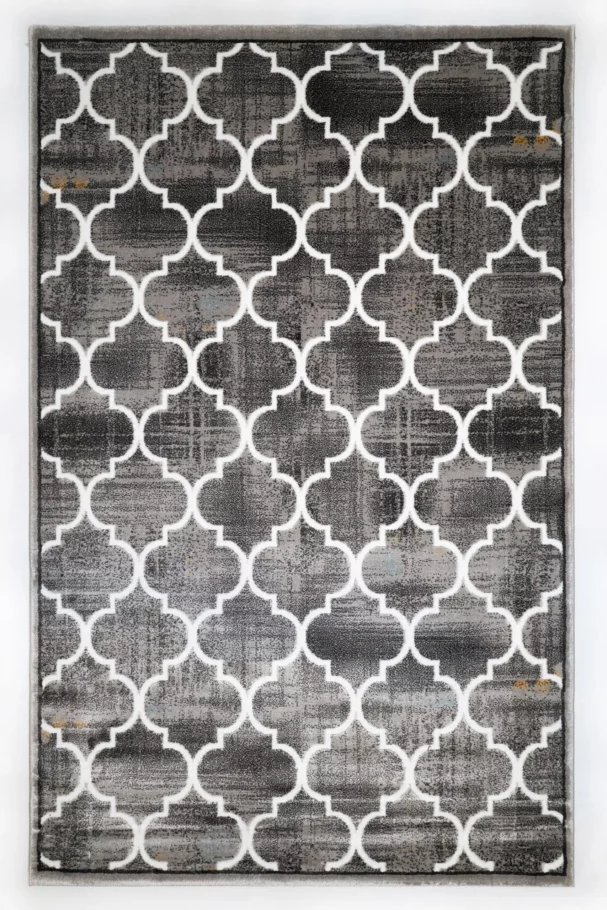A high-quality, close-up image of a Qaleen Carpets rug with a repeating, white, four-leaf pattern on a dark, grey background