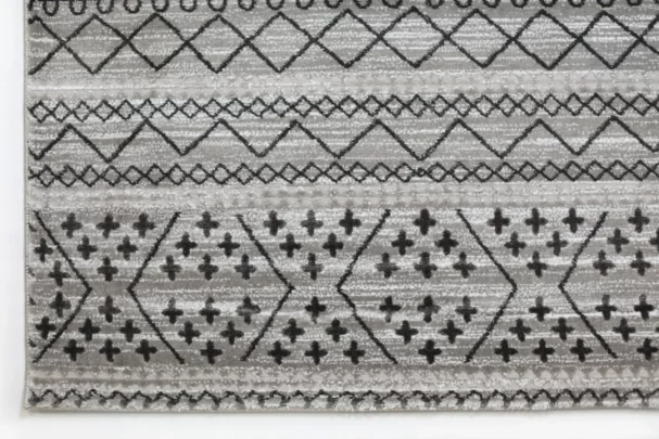 A close-up of a gray and white area rug with a geometric pattern, made by Qaleen Carpets