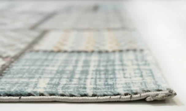 A close-up of a rug's edge, with a focus on its intricate weaving and Qaleen Carpets' quality