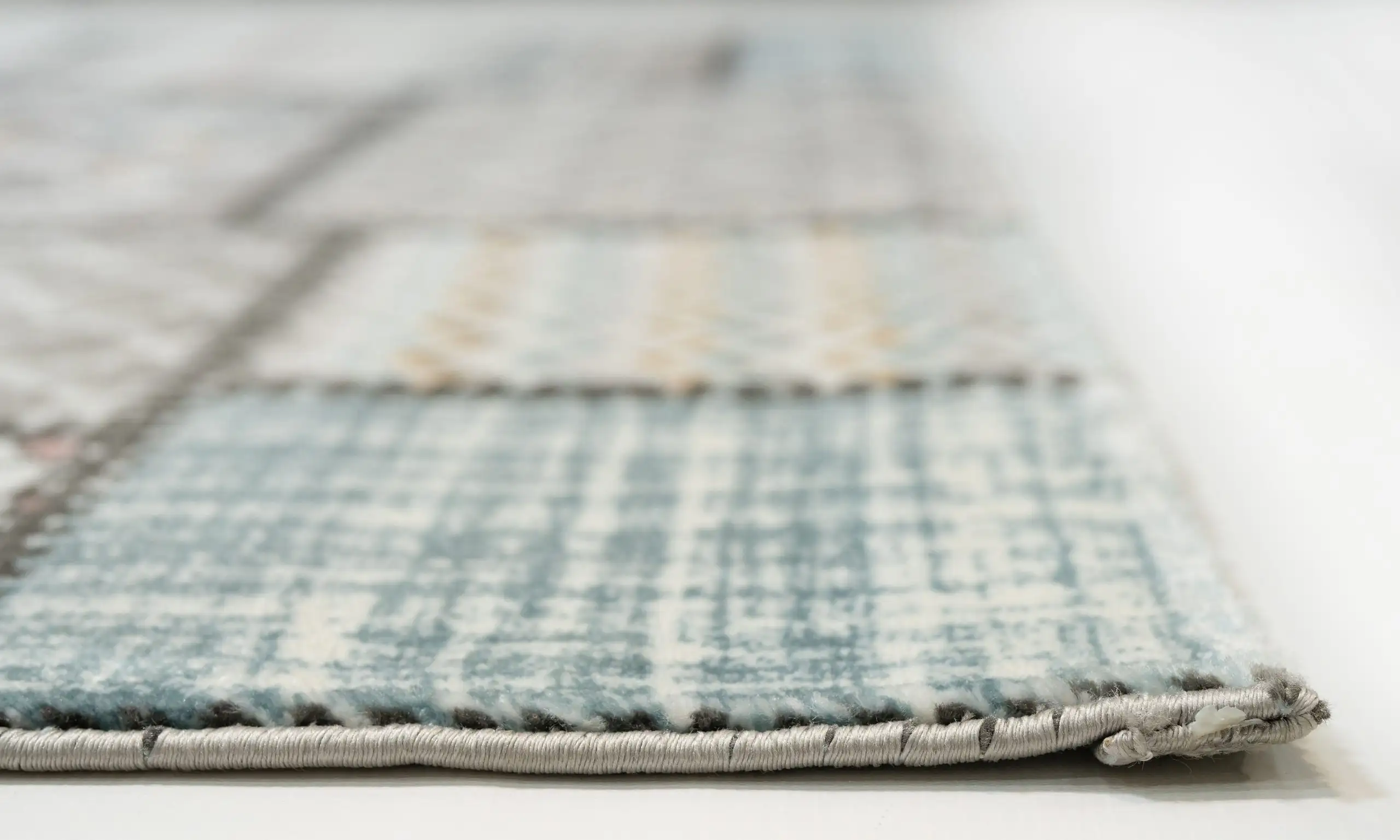 A close-up of a rug's edge, with a focus on its intricate weaving and Qaleen Carpets' quality