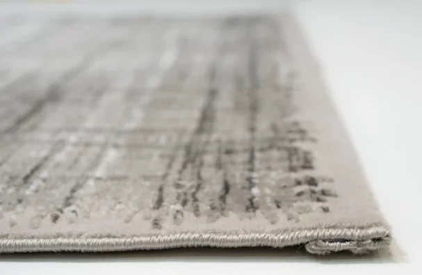 A close-up of a light grey and white woven carpet with a subtle, intricate pattern, made by Qaleen Carpets