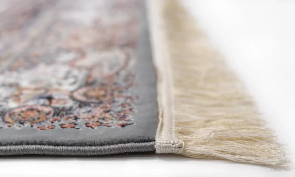 A close-up of a Qaleen Carpets rug with a fringe, showcasing its intricate design and high-quality materials
