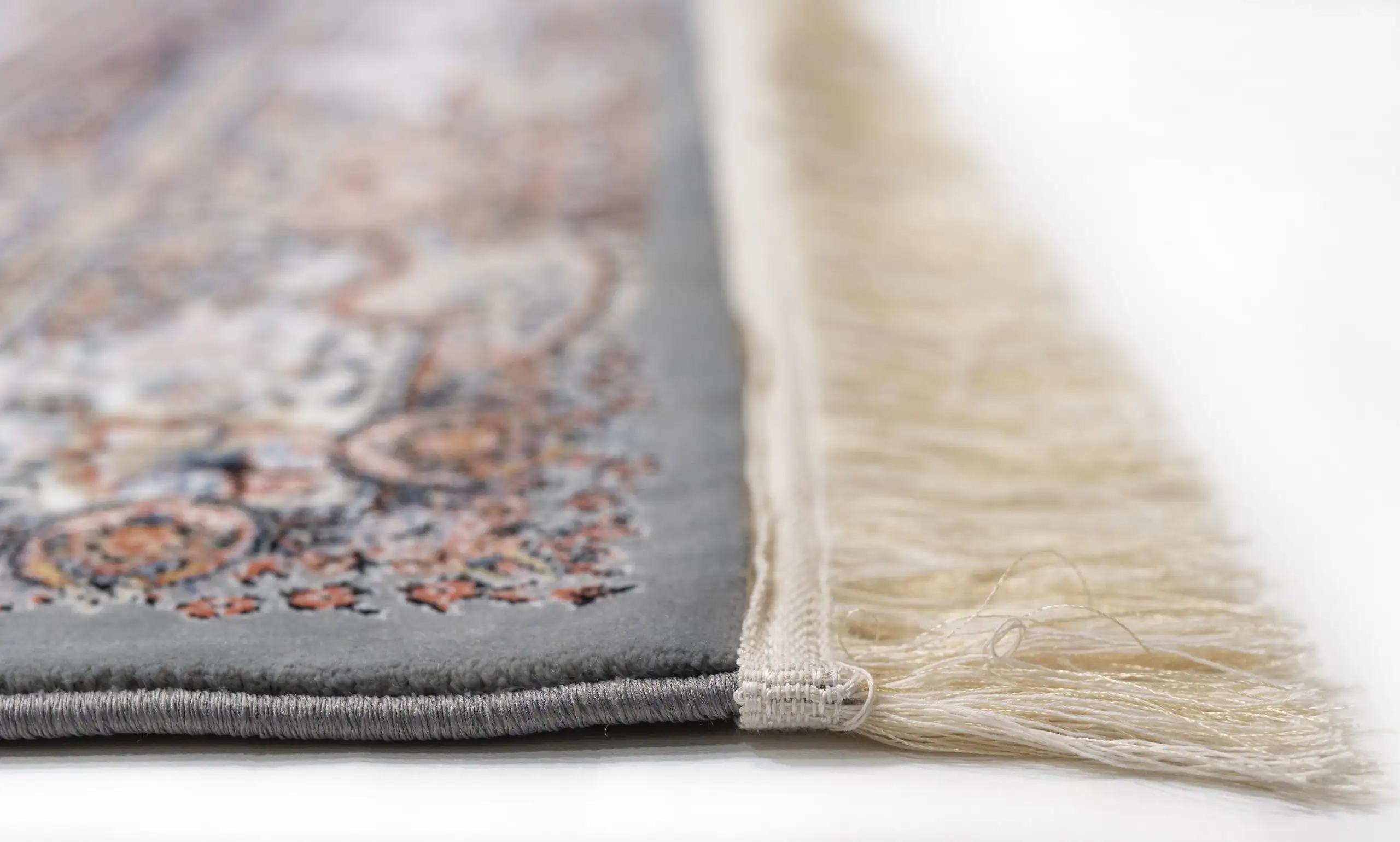 A close-up of a Qaleen Carpets rug with a fringe, showcasing its intricate design and high-quality materials