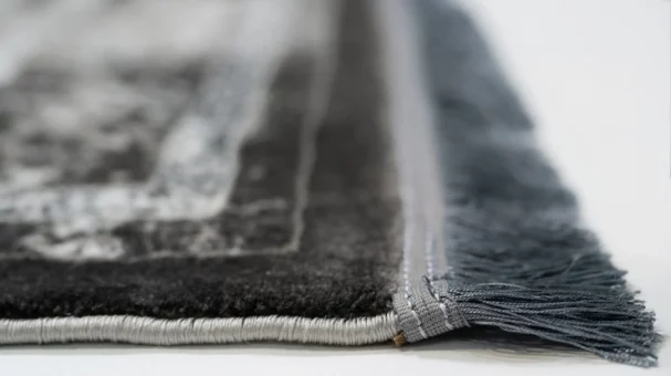 A close-up of a Qaleen Carpets rug's edge, with a focus on its fringe and border