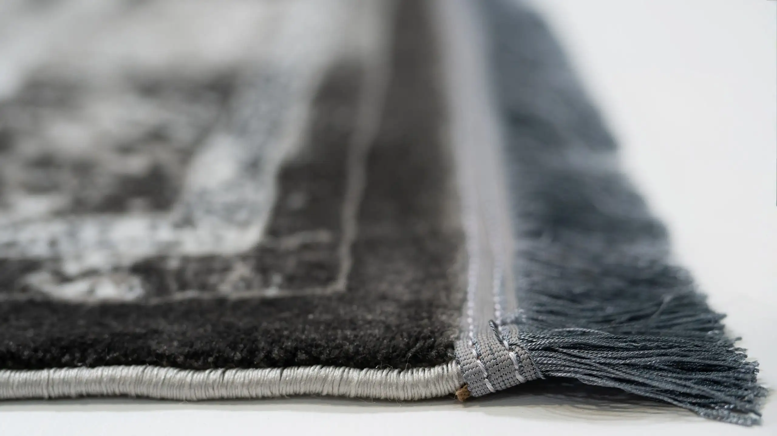 A close-up of a Qaleen Carpets rug's edge, with a focus on its fringe and border