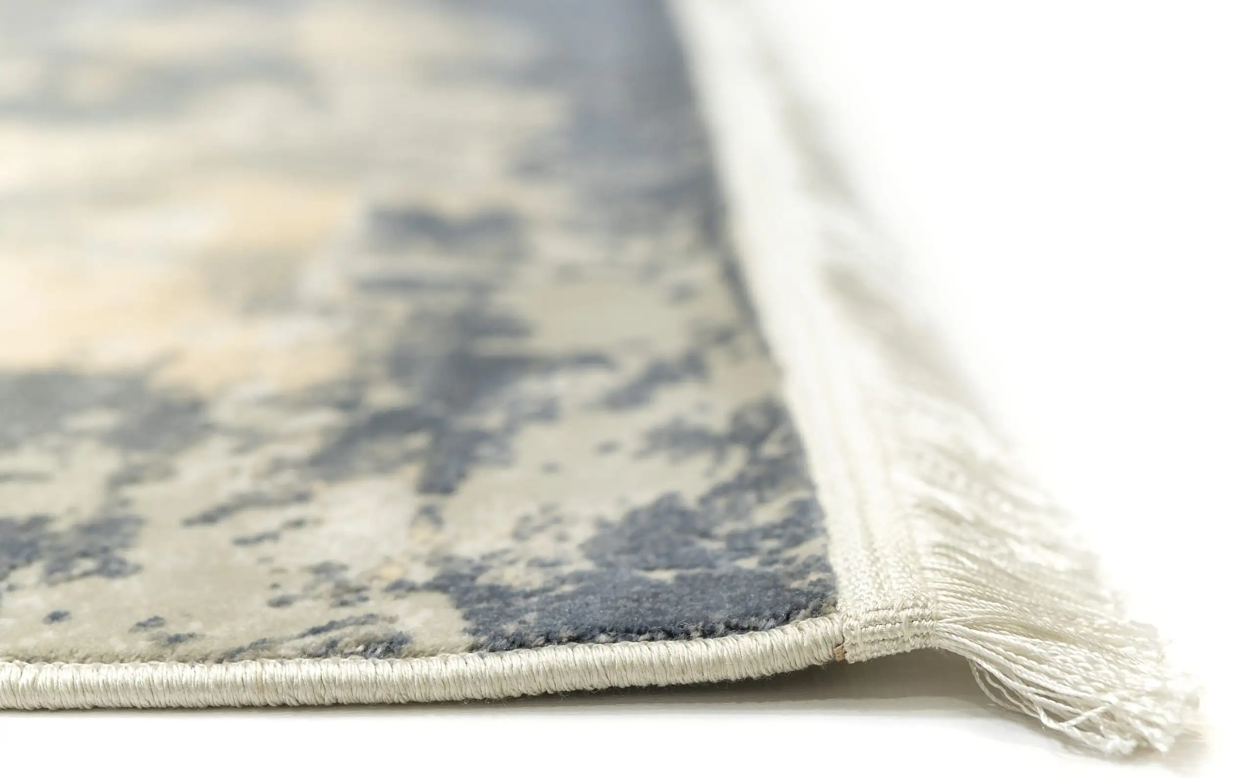A close-up of a Qaleen Carpets rug's edge, showcasing its intricate design and soft, white fringe