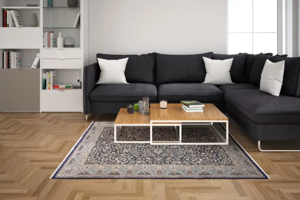 Carpets A living room with a dark grey couch, a coffee table, and a rug on the floor, featuring a mix of modern and