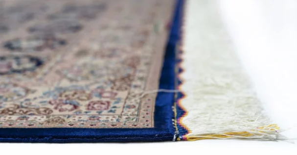 Qaleen Carpets' Persian-style rug features a cream-colored background with a blue border and intricate floral patterns in
