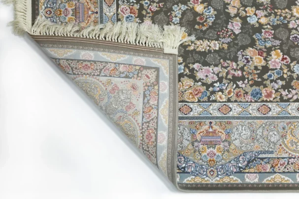 A Qaleen Carpets rug with a floral pattern and fringe, partially unrolled to show its design and quality