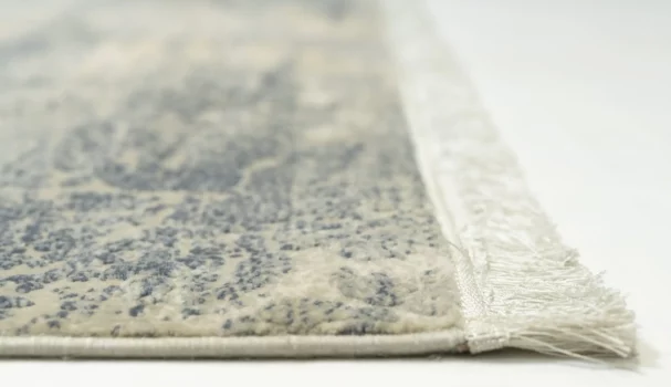 A close-up of a rug with a fringe on its edge, made by Qaleen Carpets