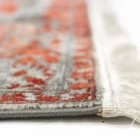 A close-up of a rug's edge, with a focus on the intricate pattern and the frayed, white, and red-tinged edges, made by