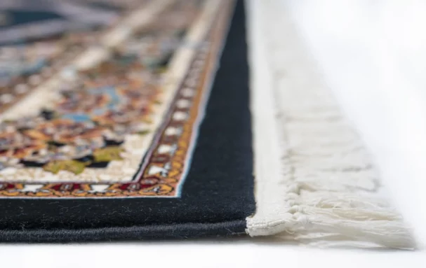 A close-up of a rug's edge, with a focus on its intricate design and Qaleen Carpets' quality