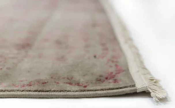 A close-up of a Qaleen Carpets rug with a subtle, intricate design and a soft, muted color palette, featuring a delicate