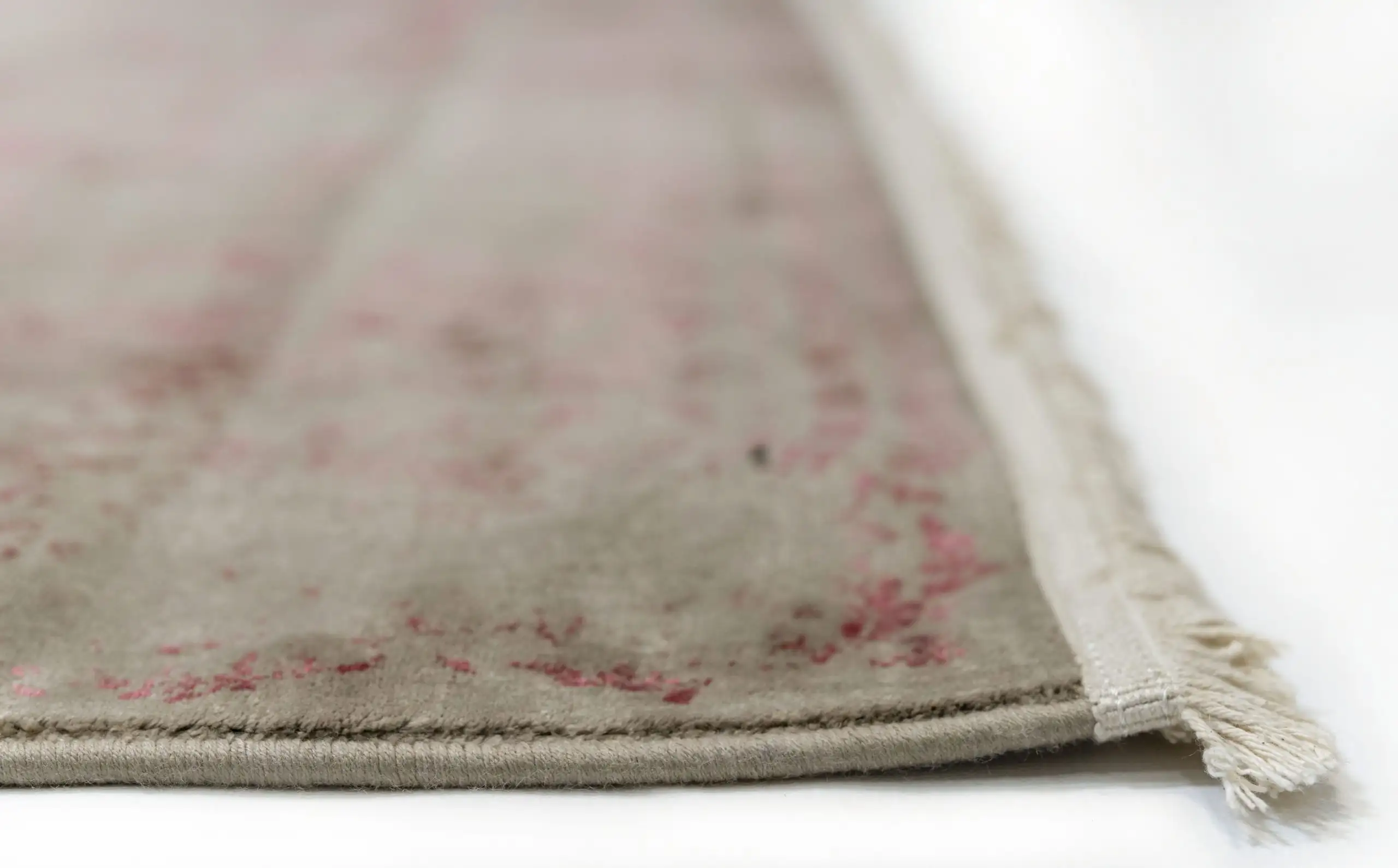 A close-up of a Qaleen Carpets rug with a subtle, intricate design and a soft, muted color palette, featuring a delicate